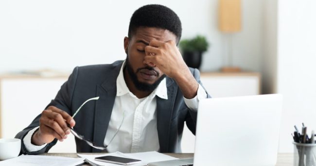 Overworked businessman sitting at workplace after hard day in office managing stress in the workplace