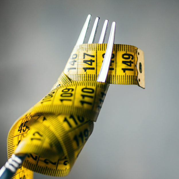 Measuring tape on a fork closeup, weight loss eating disorder signs