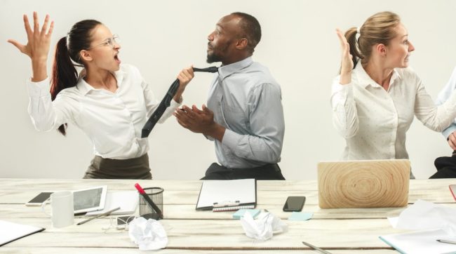 Young men and women sitting at office and working on laptops. Emotions concept managing stress