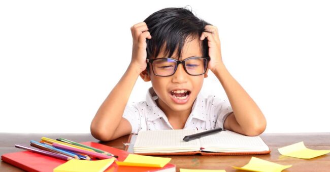 Stressed asian boy studying while holding his head. Isolated on white background back to school stress