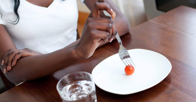 Teen girl eating a tomato eating disorders