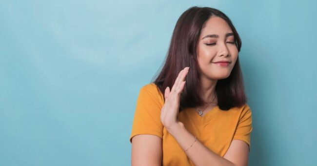Stop. Concerned Asian woman showing refusal sign, saying no, raise awareness, standing over blue background setting boundaries to reduce stress