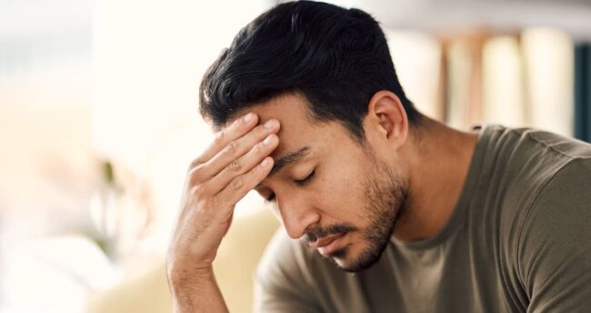 Tired, headache and stress of man in living room with mental health, fatigue and sad problem. Face, depression and frustrated male person with anxiety, brain fog or crisis of failure, mistake or debt understanding stress triggers