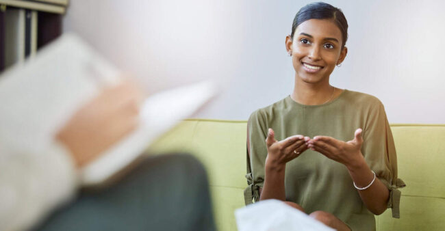 Therapy, psychology and young woman talking of help, support or mental health solution and therapist writing notes. Counseling service, progress and psychologist with indian patient, client or person therapists and insurance